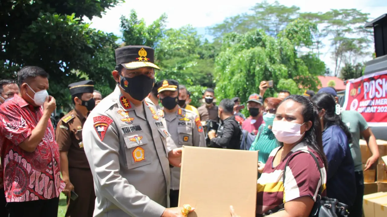 Seorang warga lansia menerima paket sembako gratis saat mengikuti vaksinasi yang digelar oleh Polda Sulut.