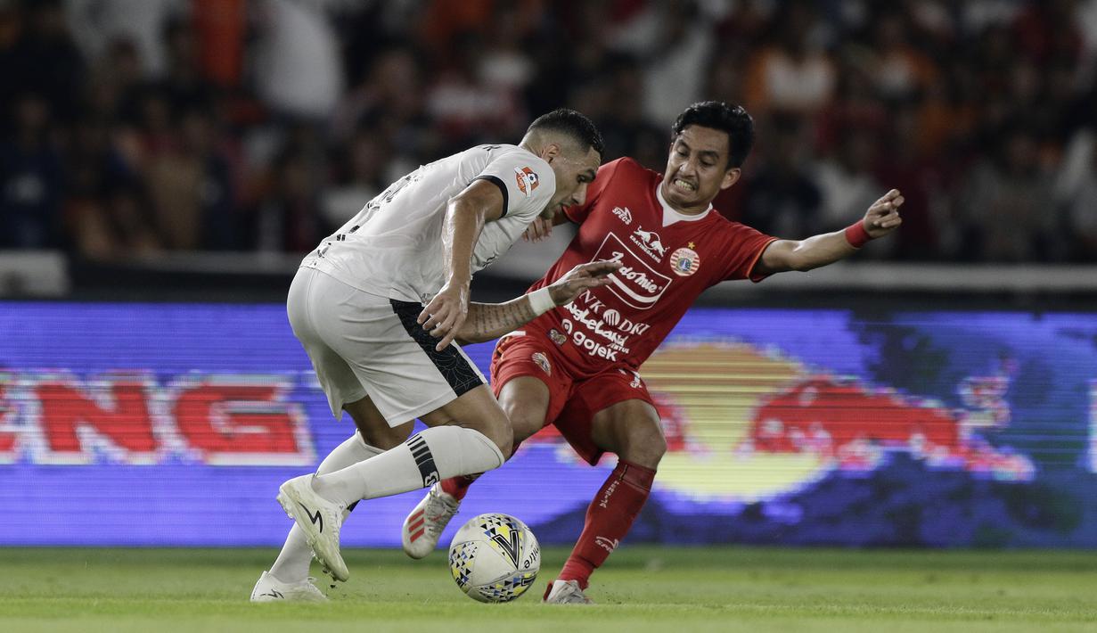Gelandang Persija Jakarta, Fitra Ridwan, berebut bola dengan bek Madura United, Jaimerson Xavier, pada laga Shopee Liga 1 di SUGBK, Jakarta, Jumat (13/12). Persija menang 4-0 atas Madura. (Bola.com/Yoppy Renato)