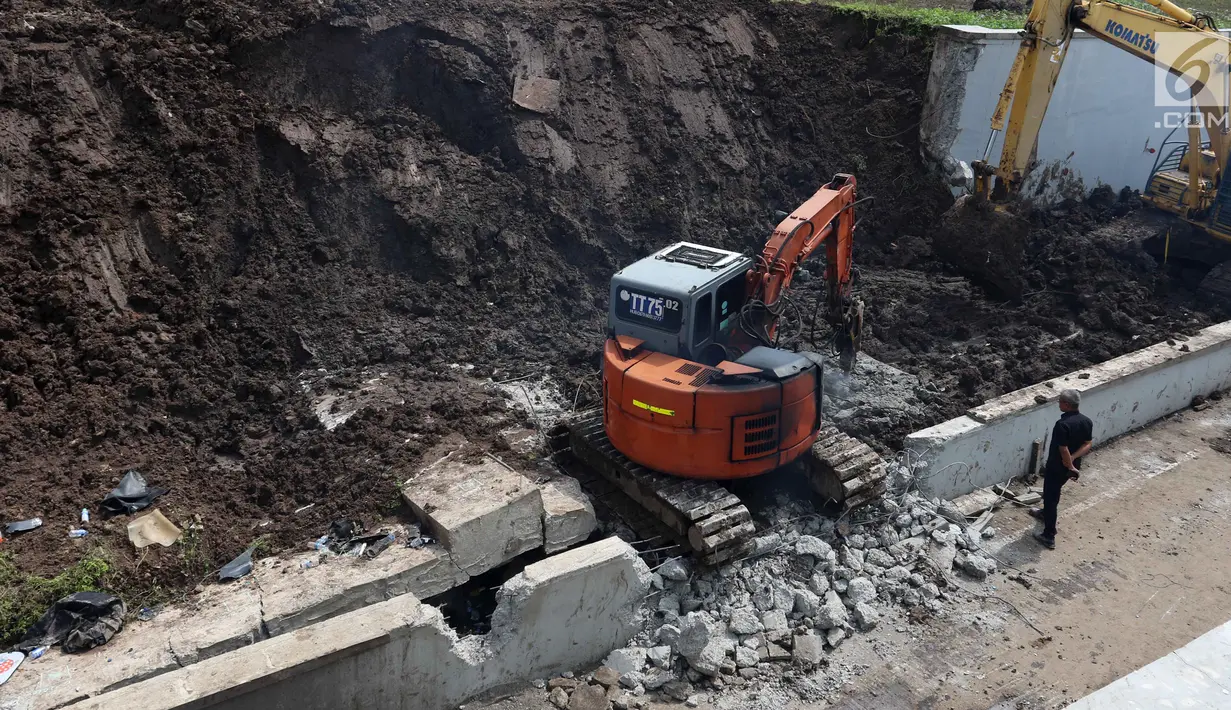 Alat berat menghancurkan beton untuk mengevakuasi mobil yang tertimbun longsor di Underpass Perimeter, Bandara Soetta, Tangerang, Banten, Selasa (6/2). Enam alat berat dikerahkam untuk proses tersebut. (Liputan6.com/Angga Yuniar)