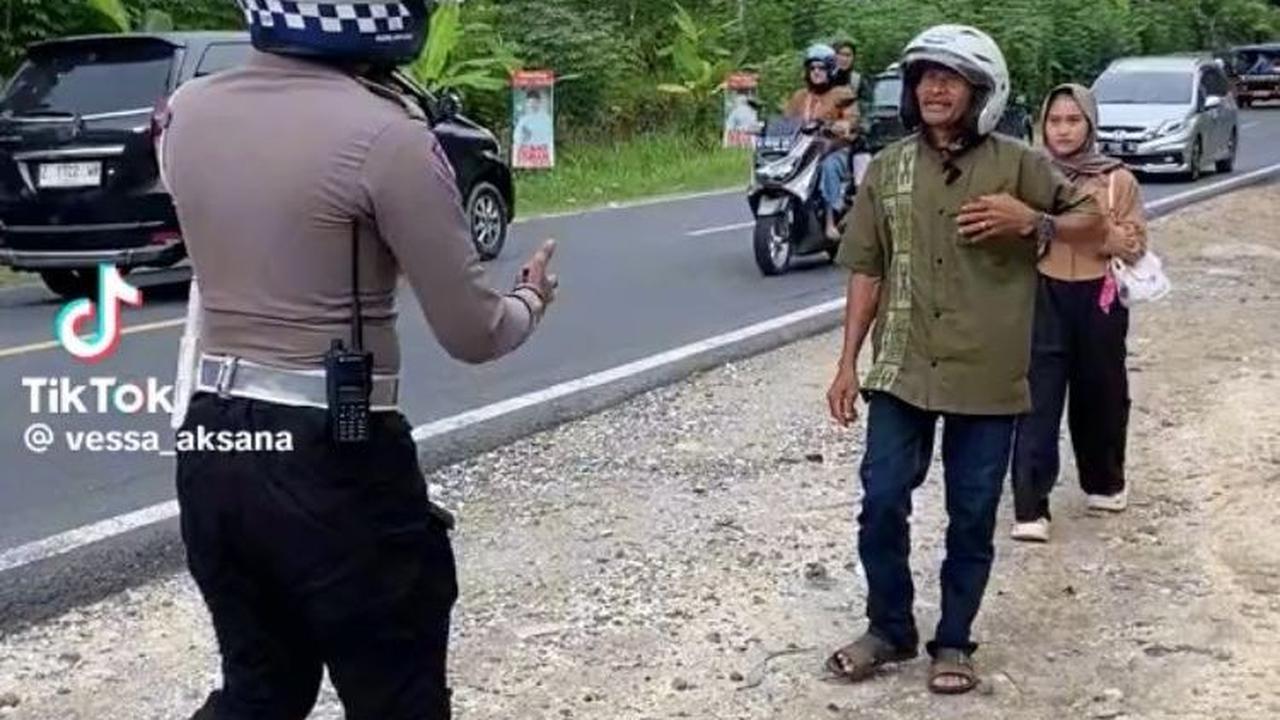 Awalnya, seorang bapak dan anaknya turun dari motor karena motor mereka mengalami masalah. Seorang petugas polisi pun langsung menghampiri bapak dan anak ini.
