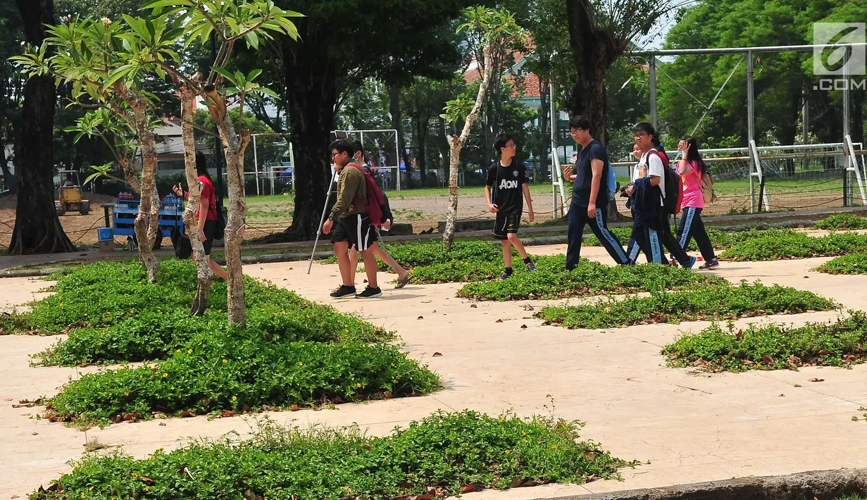 Sejumlah remaja melintasi taman di Lapangan Banteng, Jakarta, Sabtu (7/10). Pemprov DKI Jakarta menyakini usai revitalisasi ini, kawasan Lapangan Banteng akan menjadi kawasan destinasi wisata baru setelah Monas. (Liputan6.com/Helmi Afandi)