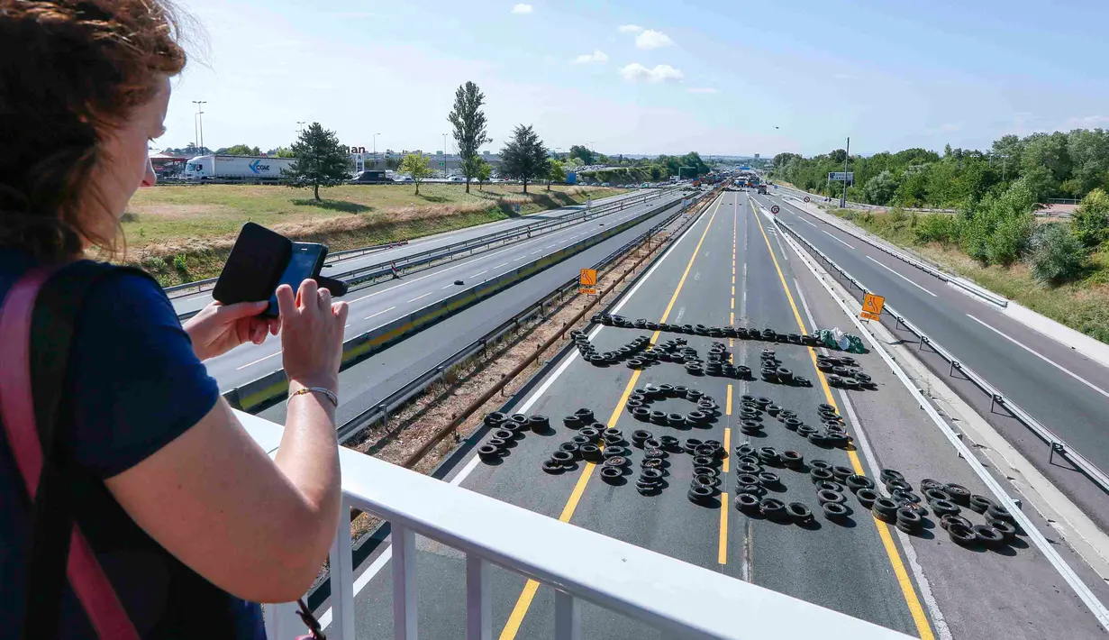 Seorang warga mengambil gambar bertuliskan " Valls, we're waiting for you", yang ditujukan untuk Perdana Menteri Perancis, Manuel Valls di Jalan raya A6 Limonest, Lyon, Prancis, (23/7/2015). (REUTERS/Robert Pratta)