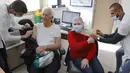 Pasangan Zvi (93) dan Yossefta (84) menerima dosis keempat vaksin covid-19 Pfizer-BioNTech di Clalit Healthcare Services di Tel Aviv, Senin (3/1/2022). Israel menyetujui pemberian dosis booster tersebut kepada kelompok warga berusia di atas 60 tahun dan tenaga medis. (JACK GUEZ/AFP)