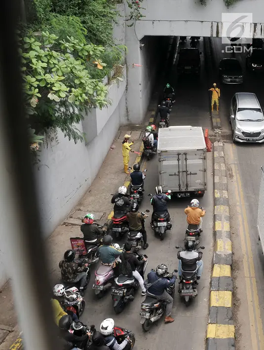 Petugas Bina Marga mengatur arus lalu lintas yang terjebak kemacetan akibat penutup selokan ambles di kolong Manggarai, Jakarta, Kamis (14/3). Penutup selokan tersebut kembali ambles meski sudah diperbaiki berkali-kali. (merdeka.com/Iqbal Nugroho)