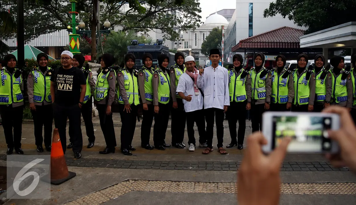 Massa Aksi 4 November 2016 melakukan foto bersama Polwan Cantik di depan Balai Kota, Jakarta, Jumat (4/11). Polwan cantik yang berjaga saat demo ini laris dan memukau para pendemo untuk berfoto bersama. (Liputan6.com/Johan Tallo)