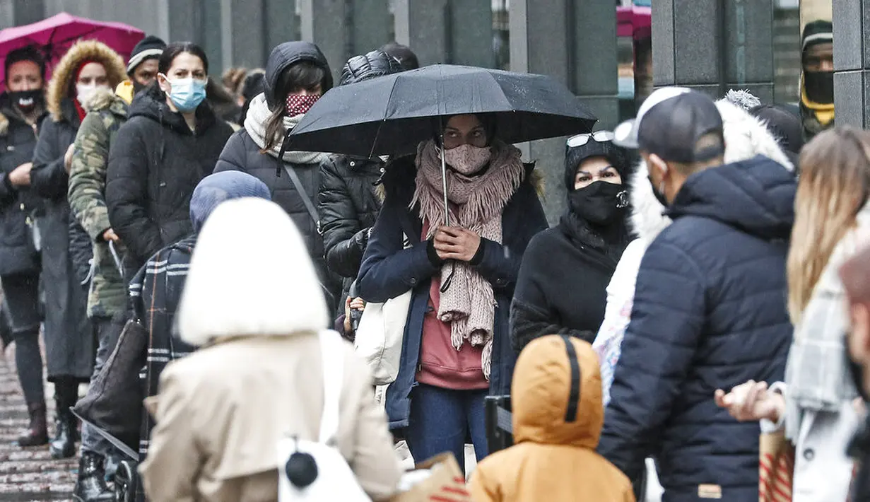 Orang-orang mengantre di depan sebuah toko di pusat Kota Essen, Jerman, Senin (14/12/2020). Jerman melakukan lockdown nasional pada 16 Desember 2020 untuk memerangi pandemi COVID-19. (AP Photo/Martin Meissner)