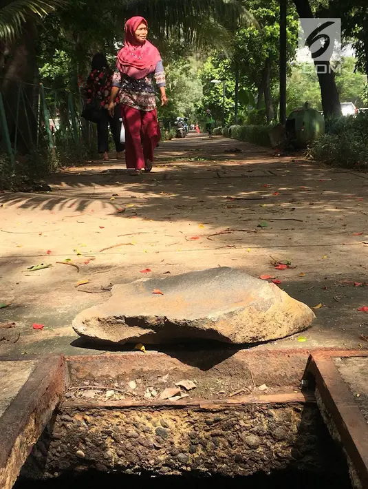 Pejalan kaki melintasi trotoar yang rusak dan berlubang di Jalan Kyai Tapa, Jakarta, Kamis (24/1). Banyaknya lubang akibat kerusakan penutup saluran air tersebut membahayakan pejalan kaki. (Liputan6.com/Immanuel Antonius)