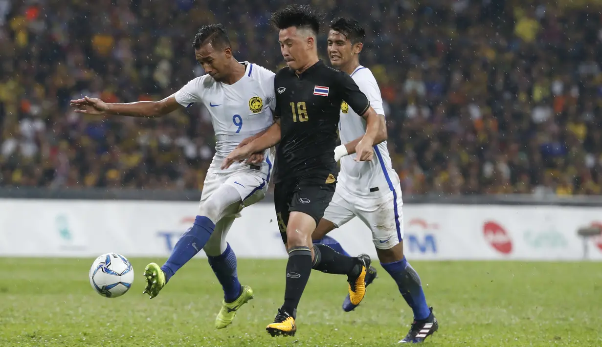 Pemai Thailand, player Worachit Kanitsribumphen (tengah) berusaha merebut bola dari pemain Malaysia, Adam Nor Azlin (kiri) pada final sepak bola putra SEA Games 2017 di Stadion Shah Alam, Malaysia (29/8/2017). Tahailand menang 1-0. (AP/Vincent Thian)