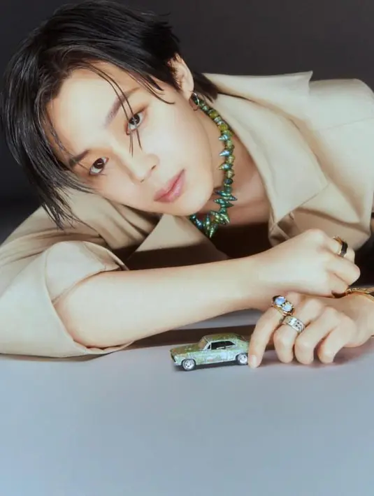 Foto lainnya memperlihatkan Jimin mengenakan atasan warna krem dan kalung berwarna hijau.