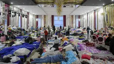 Pengungsi yang melarikan diri dari invasi Rusia ke Ukraina duduk di dalam ballroom yang menjadi tempat penampungan pengungsi darurat di hotel & spa bintang 4, di Suceava, Rumania, 4 Maret 2022. Lebih dari 2.000 orang dan 100 hewan peliharaan berlindung di dalam ballroom. (AP Photo/Andreea Alexandru)