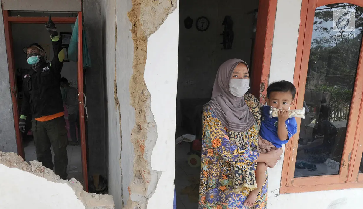 Warga menggendong anak kecil di rumah yang rusak setelah gempa mengguncang Mandalawangi, Pandeglang, Banten, Sabtu (3/8/2019). Gempa Banten mengakibatkan ratusan rumah warga mengalami kerusakan dengan kategori ringan hingga berat. (merdeka.com/Arie Basuki)