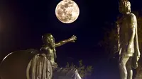 Penampakan super snow moon di antara Alexander the Great (kanan) dan Diogenes of Sinope (kiri) di Corinth, Yunani, 19 Februari 2019. (VALERIE GACHE / AFP)