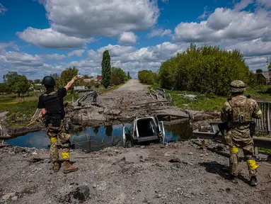 Prajurit unit pasukan khusus Ukraina Kraken berbicara dengan seorang pria di jembatan yang hancur di jalan dekat desa Rus'ka Lozova, utara Kharkiv, pada 16 Mei 2022. Ukraina mengatakan pasukannya telah menguasai kembali wilayah di Perbatasan Rusia dekat kota terbesar kedua di negara itu Kharkiv, yang terus-menerus diserang sejak invasi Moskow dimulai. (Dimitar DILKOFF / AFP)