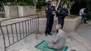 Dua anggota pasukan keamanan Israel berjaga saat seorang jemaah Palestina melaksanakan salat Jumat selama bulan suci Ramadan di tengah krisis pandemi coronavirus di luar kompleks masjid al-Aqsa di Kota Tua Yerusalem (15/5/2020). (AFP/Ahmad Gharabli)