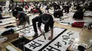 Sejumlah peserta menulis tulisan Jepang saat mengikuti lomba kaligrafi Tokyo, Jepang (5/1). Secara tradisi, masyarakat Jepang biasanya menulis harapan-harapan mereka, atau huruf keberuntungan dalam menyambut tahun baru. (AFP Photo/Behrouz Mehri)