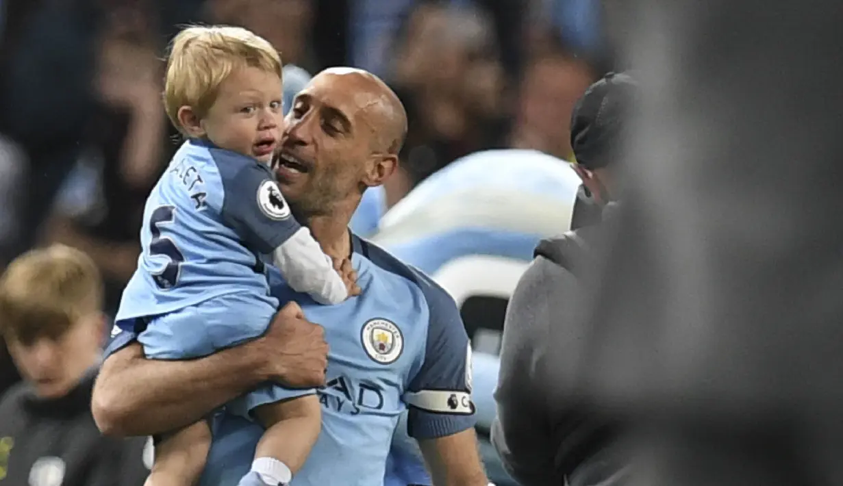 Bek Manchester City, Pablo Zabaleta, menggendong anaknya usai pertandingan Liga Inggris melawan West Bromwich Albion di Stadion Etihad, Selasa, (16/05/2017). Zabaleta resmi pamit dari klub Manchester City. (AFP/Paul Ellis)