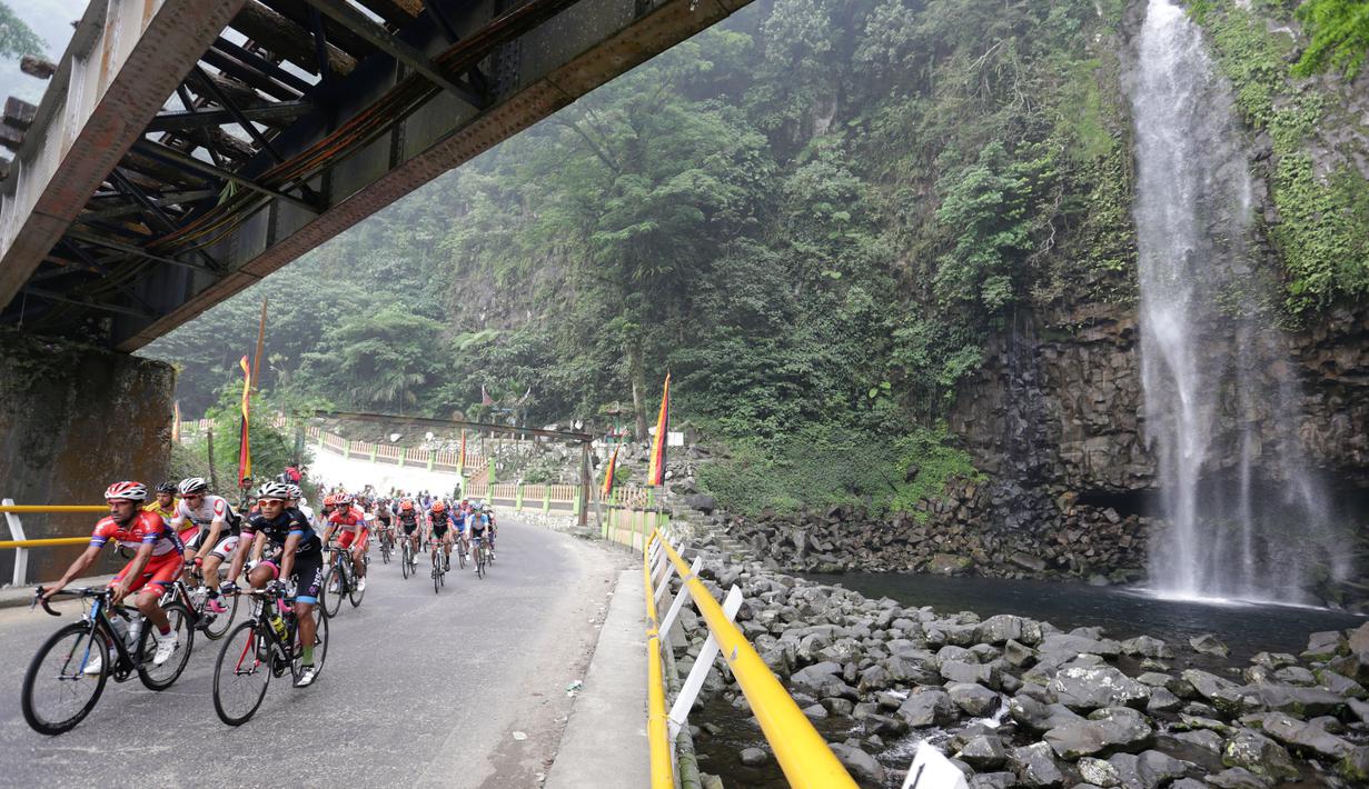 Para pebalap sedang melewati air terjun Lembah Anai, Kabupaten Tanah Datar dalam Etape 6 Tour de Singkarak 2015, Kamis (8/10/2015). (Bola.com/Arief Bagus)