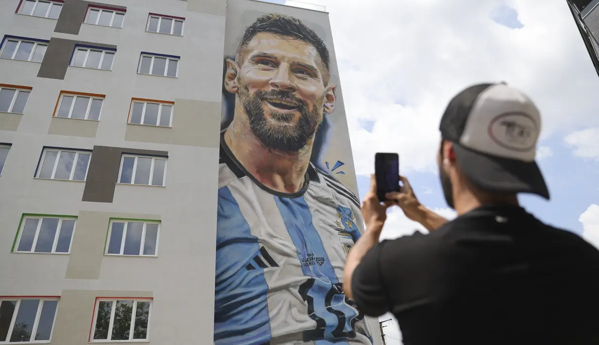 Seniman jalanan Argentina Maximiliano Bagnasco mengambil foto mural yang menggambarkan superstar sepak bola Argentina Lionel Messi, yang ia lukis, di Tirana, Albania, pada Kamis (8/6/2023). (AP Photo/Llazar Semini)