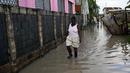 Seorang wanita berjalan melalui jalan yang banjir setelah Badai Lisa di Belize City, Belize, 3 November 2022. Badai Tropis Lisa menyebabkan banjir dan membuat sebagian negara itu menjadi gelap gulita. (Johan ORDONEZ/AFP)