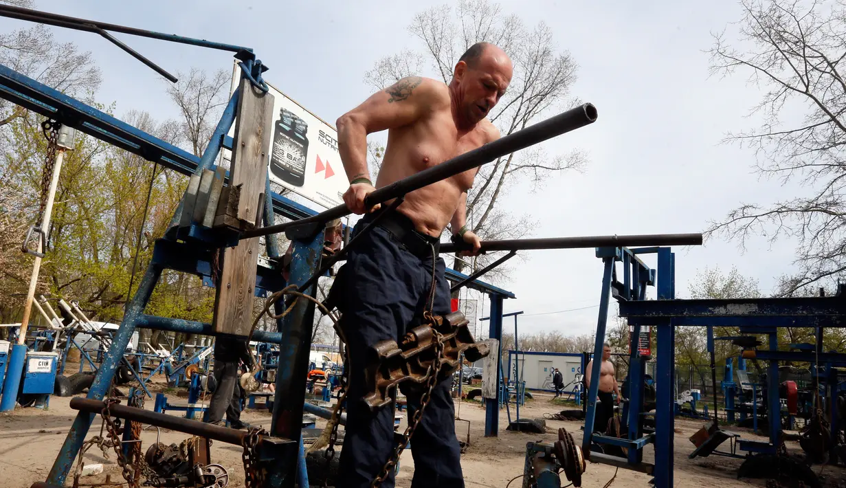 Seorang pria berlatih mengangkat beban tubuhnya di outdoor gym atau pusat kebugaran terbuka di tepi Sungai Dnipro, Kiev, Ukraina, Kamis (18/4). Meskipun kurang mewah, tempat kebugaran ini ternyata banyak peminatnya. (AP Photo/Efrem Lukatsky)