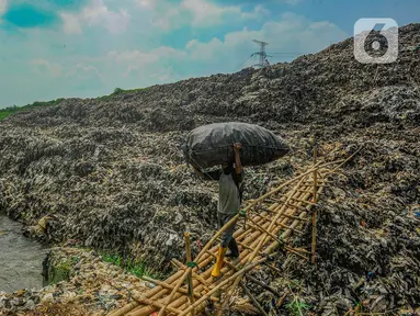 Warga membawa sampah daur ulang melewati lokasi longsor Tempat Pembuangan Akhir (TPA) Cipayung yang menimbun Kali Pesanggrahan di Depok, Jawa Barat, Selasa (30/4/2024). (merdeka.com/Arie Basuki)