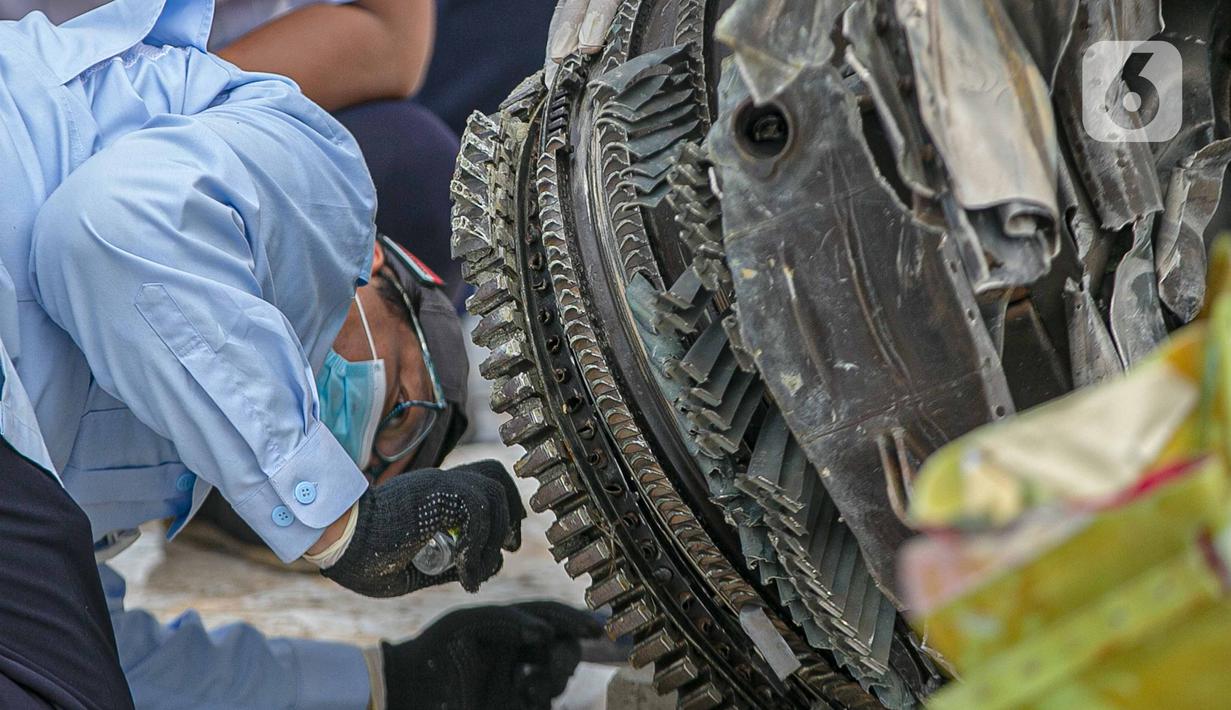 Petugas Komisi Nasional Keselamatan Transportasi (KNKT) memeriksa bagian turbin pesawat Sriwijaya Air dihari kelima yang jatuh di perairan Pulau Seribu, di Dermaga JICT, Jakarta,  Rabu (13/1/2021). Pemeriksaan itu dilakukan untuk mengetahui penyebab jatuhnya pesawat. (Liputan6.com/Faizal Fanani)