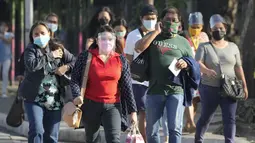 Orang-orang yang memakai masker berjalan di samping jalan di kota Quezon, Filipina, Senin (17/1/2022). Orang-orang yang belum menerima vaksin COVID-19 dilarang naik transportasi publik di ibu kota Manila mulai Senin menyusul lonjakan kasus covid varian omicron. (AP Photo/Aaron Favila)