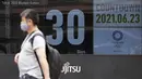 Seorang pria berjalan di depan kalender hitung mundur yang menunjukkan 30 hari menuju Olimpiade Tokyo 2020, di Tokyo, Rabu (23/6/2021). Olimpiade Tokyo dimulai pada 23 Juli dan penyelenggara mengizinkan penonton lokal menghadiri venue pertandingan dengan kapasitas 50 persen (AP Photo/Eugene Hoshiko)