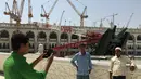 Umat muslim foto bersama dengan latar berlakang crane yang roboh di Masjidil  Haram, Kota Mekah,  Arab Saudi (9/12/2015). Sebanyak 107 calon jemaah haji meninggal dunia akibat crane jatuh karena cuaca buruk. (REUTERS / Mohamed Al Hwaity)