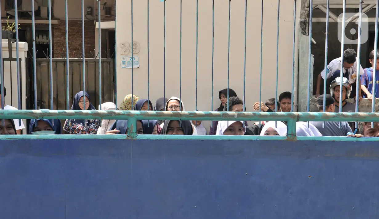 Warga menyaksikan dari luar saat kebakaran kembali terjadi di Gedung SMK Yadika 6, Jatiwaringin, Pondok Gede, Kota Bekasi, Jawa Barat, Selasa (19/11/2019). Guru, siswa, dan pegawai berjibaku memadamkan api sambil menunggu petugas pemadam kebakaran datang. (merdeka.com/Iqbal Nugroho)