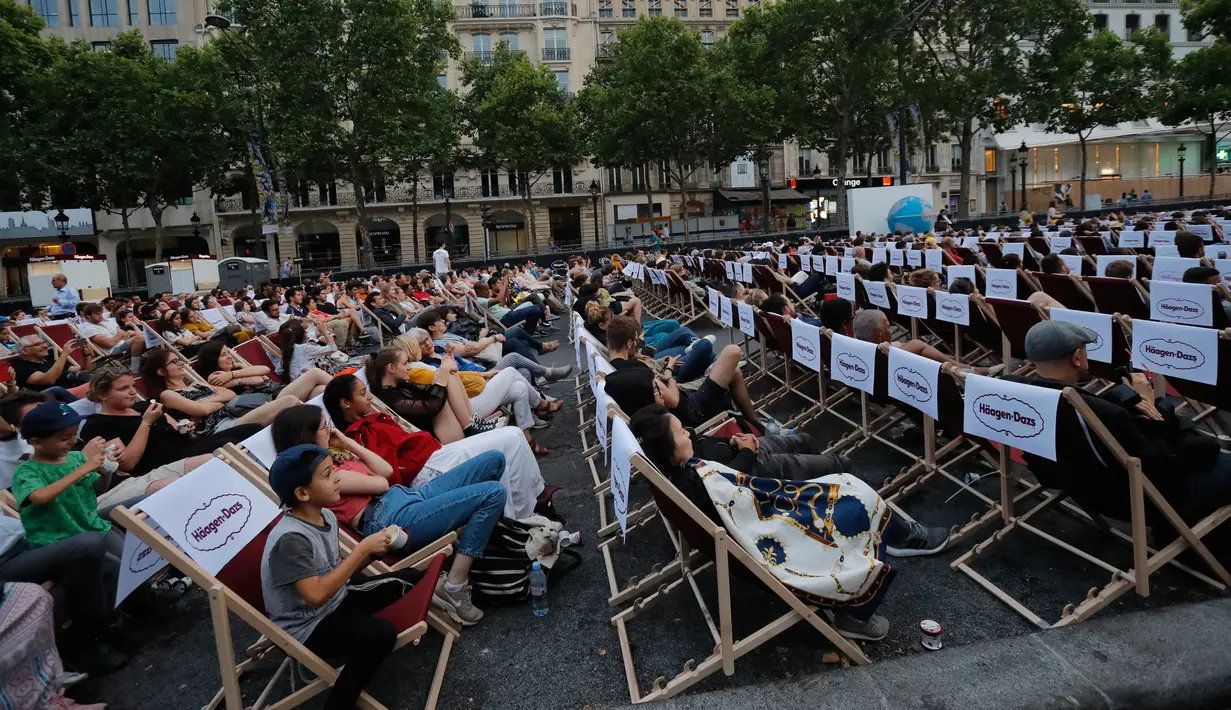 Orang-orang menonton film gratis yang diputar di ruang terbuka di jalan Champs Elysees, Paris (7/7/2019). Pemutaran bioskop luar ruangan gratis di Paris musim panas ini sudah kedua kalinya dibuat. (AP Photo/Michel Euler)