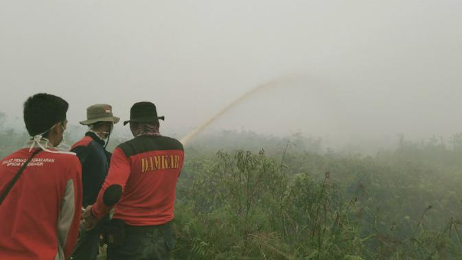 Tiga orang petugas pemadam kebakaran dari Tim Damkar Tanjab Timur saat berjibaku memadamkan Karhutla di lahan Gambut Desa Sido Mukti, Kecamatan Dendang, Tanjab Timur, Jambi. (Liputan6.com/Gresi Plasmanto)