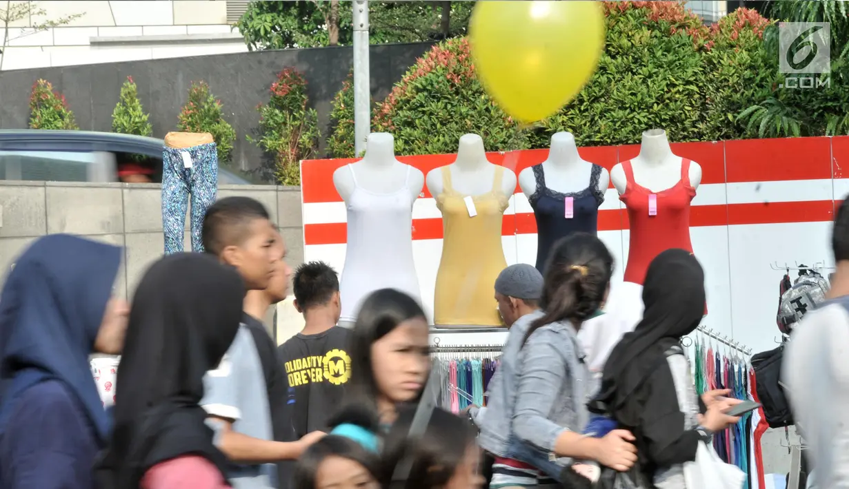 Warga melintasi lapak PKL saat car free day di MH Thamrin, Jakarta, Minggu (8/9/2019). Penutupan sebagian jalan akibat proyek revitalisasi trotoar membuat para PKL menggelar lapak hingga ke badan jalan sehingga menyebabkan aktivitas olahraga warga terhambat. (merdeka.com/Iqbal S. Nugroho)
