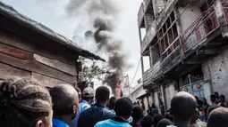 Warga berkerumun menyaksikan sebuah pesawat yang jatuh di kawasan padat penduduk, Goma, Republik Demokratik Kongo, Minggu (24/11/2019). Pihak berwenang mengatakan korban tewas terdiri dari 17 penumpang, dua awak, serta tujuh orang di darat. (PAMELA TULIZO/AFP)