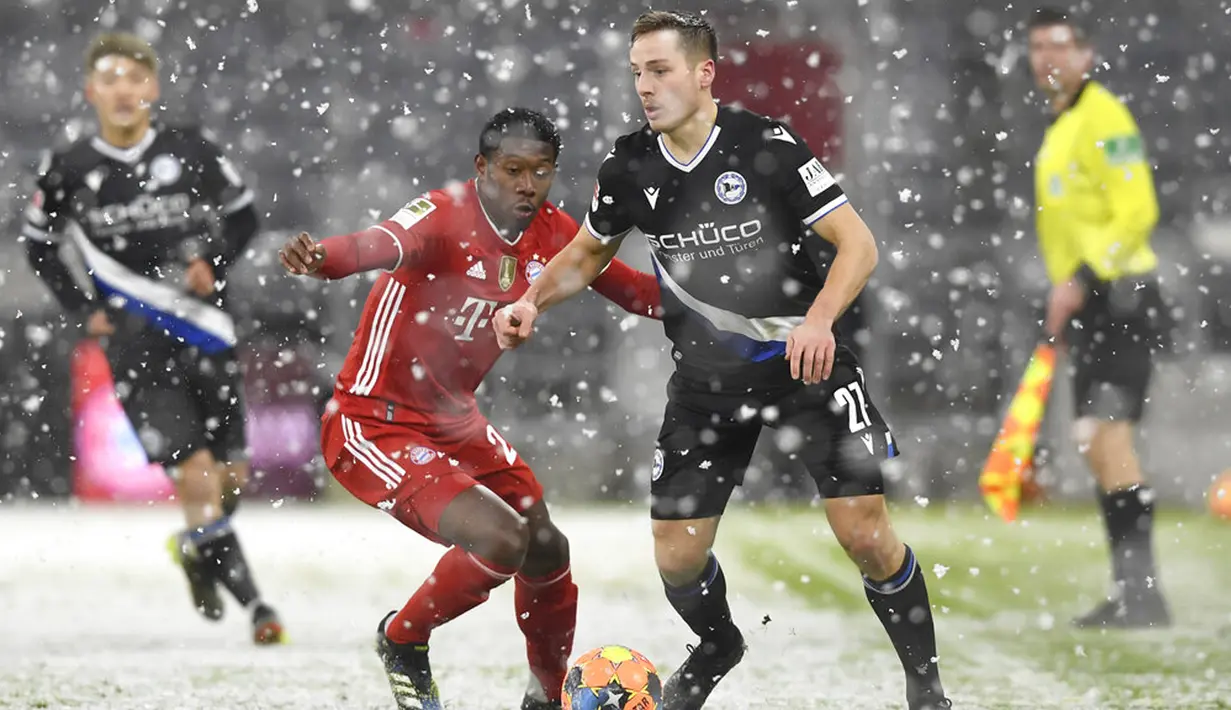 Pemain Bayern Munchen David Alaba (kiri) memperebutkan bola dengan pemain Arminia Bielefeld Cedric Brunner  pada pertandingan Bundesliga di Allianz Arena, Munich, Jerman, Senin (15/2/2021). Laga berakhir dengan skor 3-3. (AP Photo/Andreas Schaad, Pool)