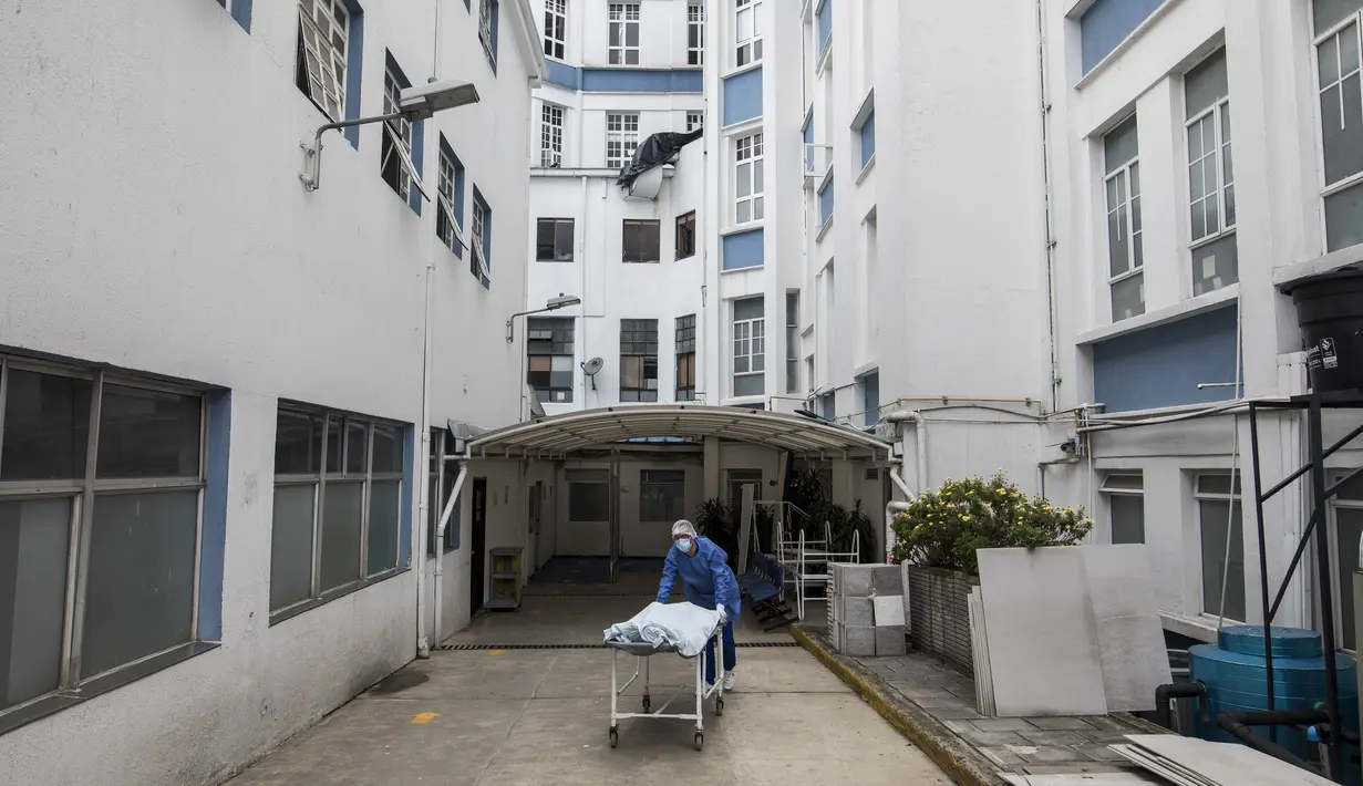 Seorang petugas kesehatan memindahkan pasien yang meninggal karena COVID-19 menuju kamar mayat di Rumah Sakit Samaritana di Bogota, Kamis (3/6/2021). Kolombia menjadi hotspot pandemi yang mengalami gelombang ketiga infeksi COVID-19 dan lonjakan kematian. (AP Photo/Ivan Valencia)