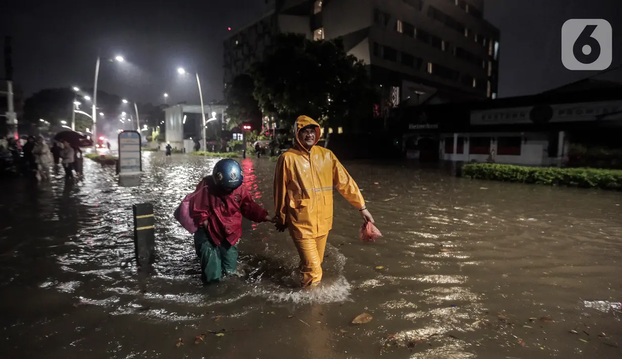 Warga melintasi banjir di Jalan Kemang Raya, Jakarta Selatan, Selasa (4/10/2022). Hujan yang mengguyur wilayah Ibu Kota Jakarta mengakibatkan banjir menggenangi kawasan Kemang, Jakarta. (Liputan6.com/Johan Tallo)