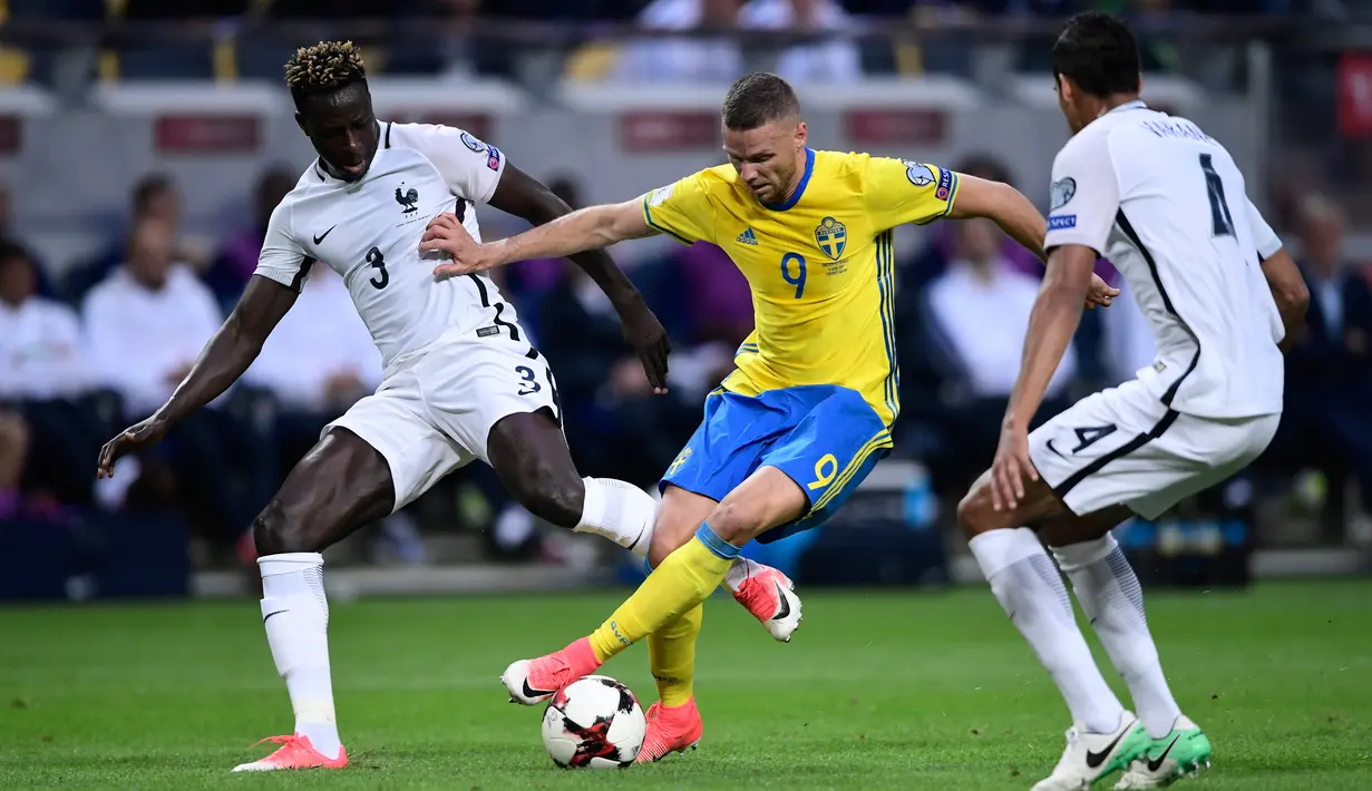 Penyerang Swedia, Marcus Berg (tengah) berusaha melewati dua pemain Prancis, Benjamin Mendy (kiri) dan Raphael Varane saat bertanding pada kualifikasi Piala Dunia 2018 di Friends Arena, Solna, Stockholm (9/6). (Marcus Eriksson/TT via AP)