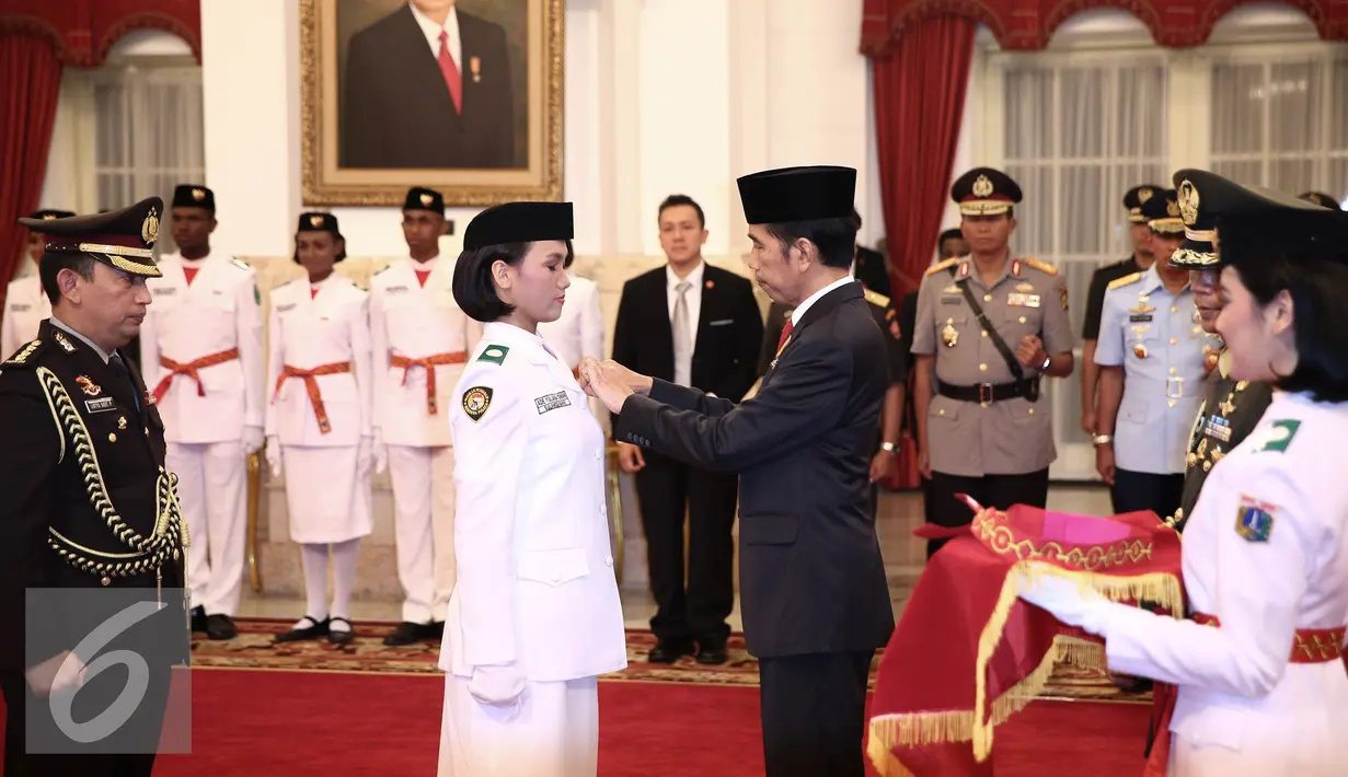 Presiden Jokowi memberikan sabuk sebagai tanda telah dikukuhkan dalam Upacara Pengukuhan Pasukan Pengibar Bendera Pusaka (Paskibraka) di Istana Negara, Jakarta, Senin (15/8). (Liputan6.com/Faizal Fanani)