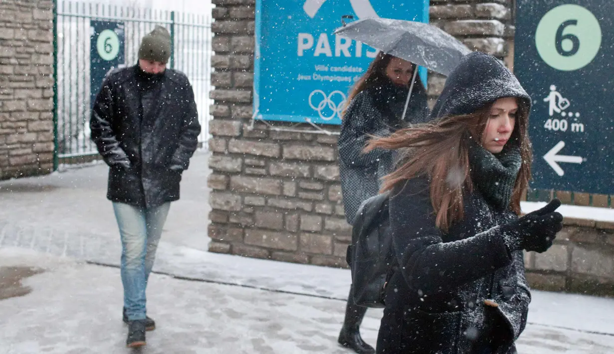 Pejalan kaki berjalan saat turun salju di Paris, Prancis, (6/2). Badan cuaca nasional Prancis Meteo France mengatakan sekitar setengah negara di eropa siaga atas bahaya tingkat salju dan es yang berbahaya. (AP Photo / Francois Mori)