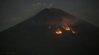 Api membakar hutan lereng Gunung Agung setelah terjadinya lontaran batu pijar dari kawah terlihat dari Karangasem, Bali, Selasa (3/7). Lontaran lava pijar pun teramati keluar kawah dengan jarak mencapai 2 ribu meter. (AP/Firdia Lisnawati)