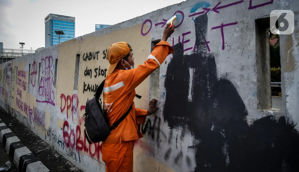 Petugas PPSU membersihkan coretan yang mengotori pembatas jalan pascaunjuk rasa di kawasan DPR/MPR, Jakarta, Jumat (17/7/2020). Coretan tersebut dilakukan oleh massa yang menolak RUU Omnibus Law Cipta Lapangan Kerja di depan Gedung DPR pada Kamis (16/7) kemarin. (Liputan6.com/Faizal Fanani)