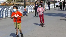 Anak-anak bermain otopet dengan memakai masker di Beirut, Lebanon, 3 Mei 2020. Lebanon telah mengurangi langkah-langkah mobilisasi umum dengan mengizinkan restoran untuk melayani sejumlah kecil pelanggan mulai 4 Mei dan menerapkan jam operasional untuk sektor-sektor lainnya. (Xinhua/Bilal Jawich)