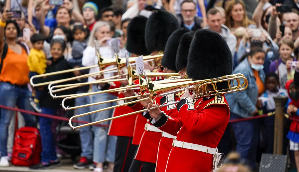 Orang-orang menyaksikan prosesi pergantian penjaga di Istana Buckingham, London, Senin (23/8/2021). Pergantian pasukan jaga yang dilengkapi dengan alat musik lengkap ala marching band tersebut berlangsung untuk pertama kalinya sejak dimulainya pandemi corona Covid-19. (AP Photo/Alberto Pezzali)