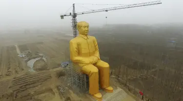 Sebuah Crane saat beroperasi di sebelah patung Presiden pertama Cina, Mao Zedong saat proses penyelesaian pembangunannya di ladang Desa Tongxu, Henan, Cina (4/1). Patung ini memiliki tinggi 36,6 meter dan dilapisi cat emas. (Reuters/Stringer)