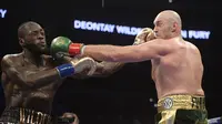 Deontay Wilder (kiri), dan Tyson Fury saling melepaskan pukulan dalam pertarungan tinju kelas berat WBC di Staples Center, Los Angeles, Minggu (2/12/2018) pagi WI. (Foto AP / Mark J. Terrill)