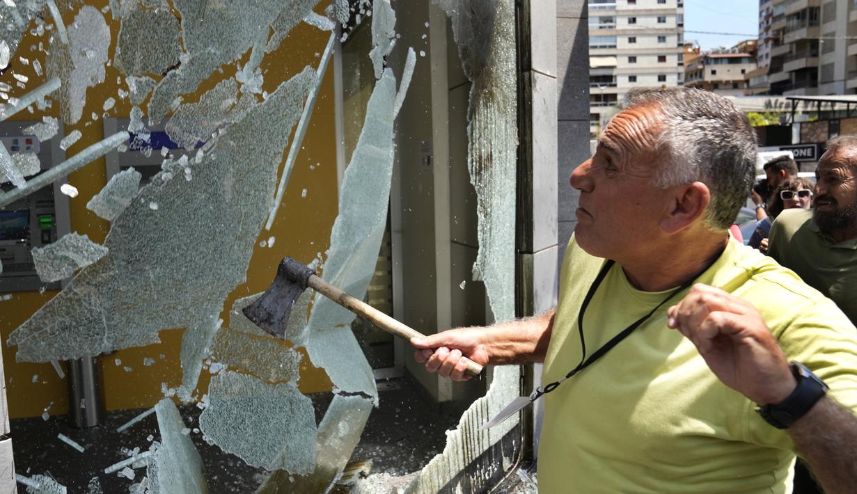 Pengunjuk rasa memecahkan jendela di Bank Byblos selama protes menuntut pembebasan tabungan para deposan yang terperangkap, di Beirut, Lebanon, Kamis, 15 Juni 2023. (AP Photo/Hussein Malla)