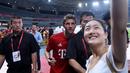 Penyerang Bayern Muenchen, Thomas Mueller berselfie bersama seorang fans usai sesi latihan di Shanghai, China, (19/7/2015). Bayern mengunjungi Cina untuk menggelar Tur Pra-musim. (AFP PHOTO/JOHANNES EISELE)