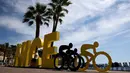 Wisatawan duduk di tulisan Nice dekat ornamen Tour de France2020 di kota Nice, French Riviera, Rabu (26/8/2020). Ajang balap sepeda lintas kota di Prancis ini akan dimulai dari kota Nice pada 29 Agustus hingga 20 September di bawah bayang-bayang ‘gelombang kedua’ COVID-19. (Kenzo Tribouillard/AFP)
