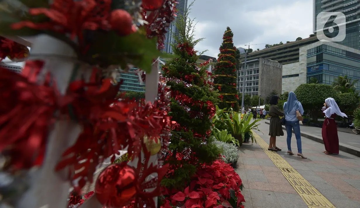 Warga berfoto dengan latar hiasan pohon Natal 2021 di Bundaran HI, Jakarta, Sabtu (25/12/2021). Libur Natal 2021 dimanfaatkan sebagian warga berfoto berlatar pohon Natal yang telah dihias atau berjalan-jalan ke mal untuk mengisi waktu berlibur bersama. (merdeka.com/Imam Buhori)